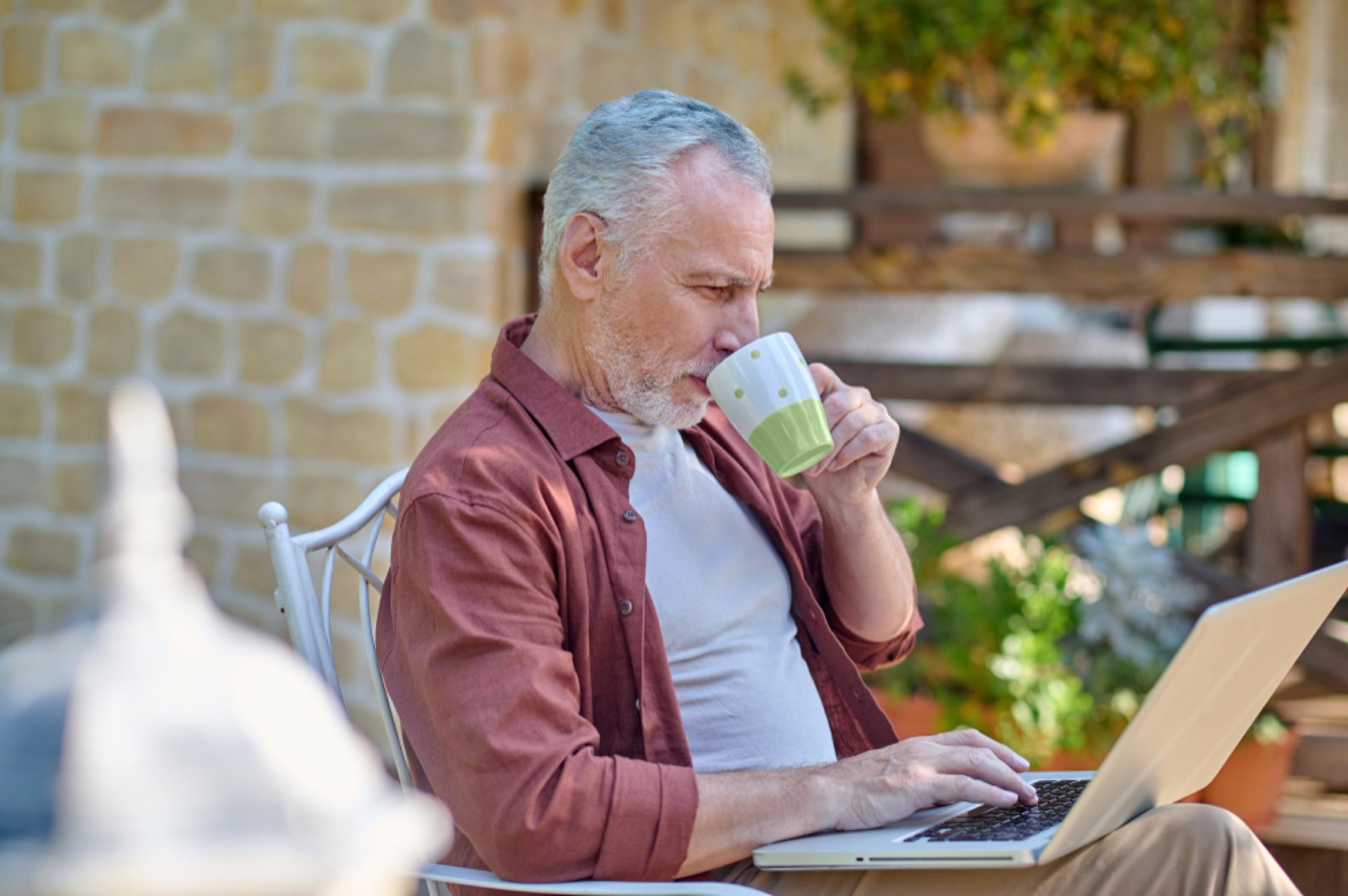 Man over 60 using a laptop outdoors